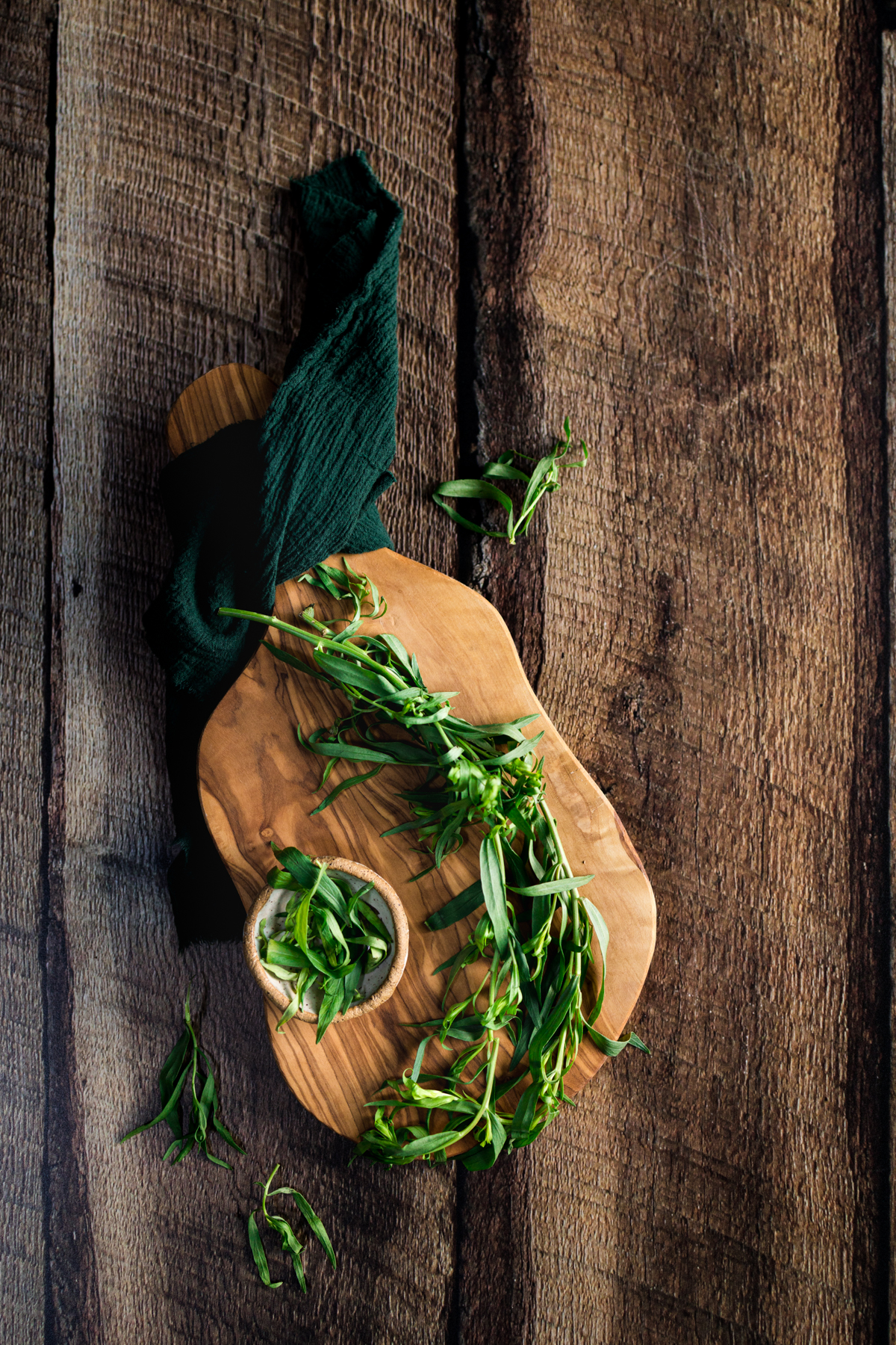 Fresh tarragon herbs on a wooden cutting board.