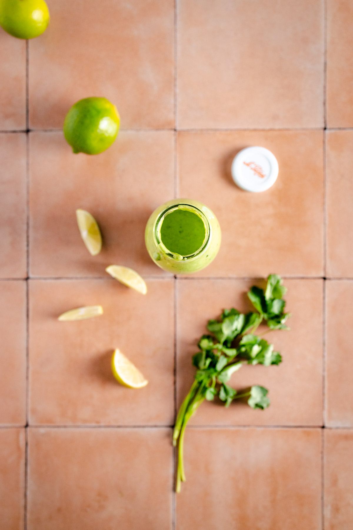 A green juice with limes and lemons on a tiled floor.