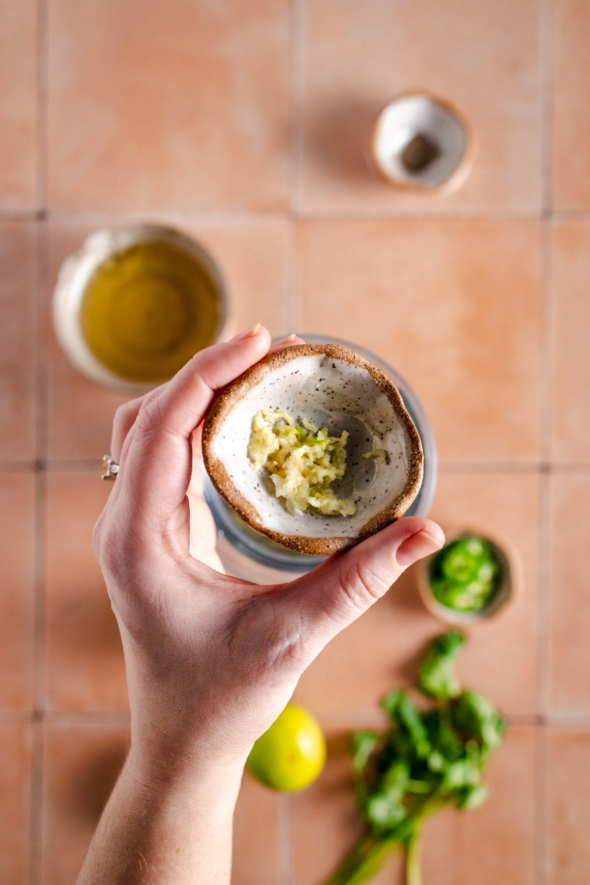 A hand holding a small bowl with a lime in it.