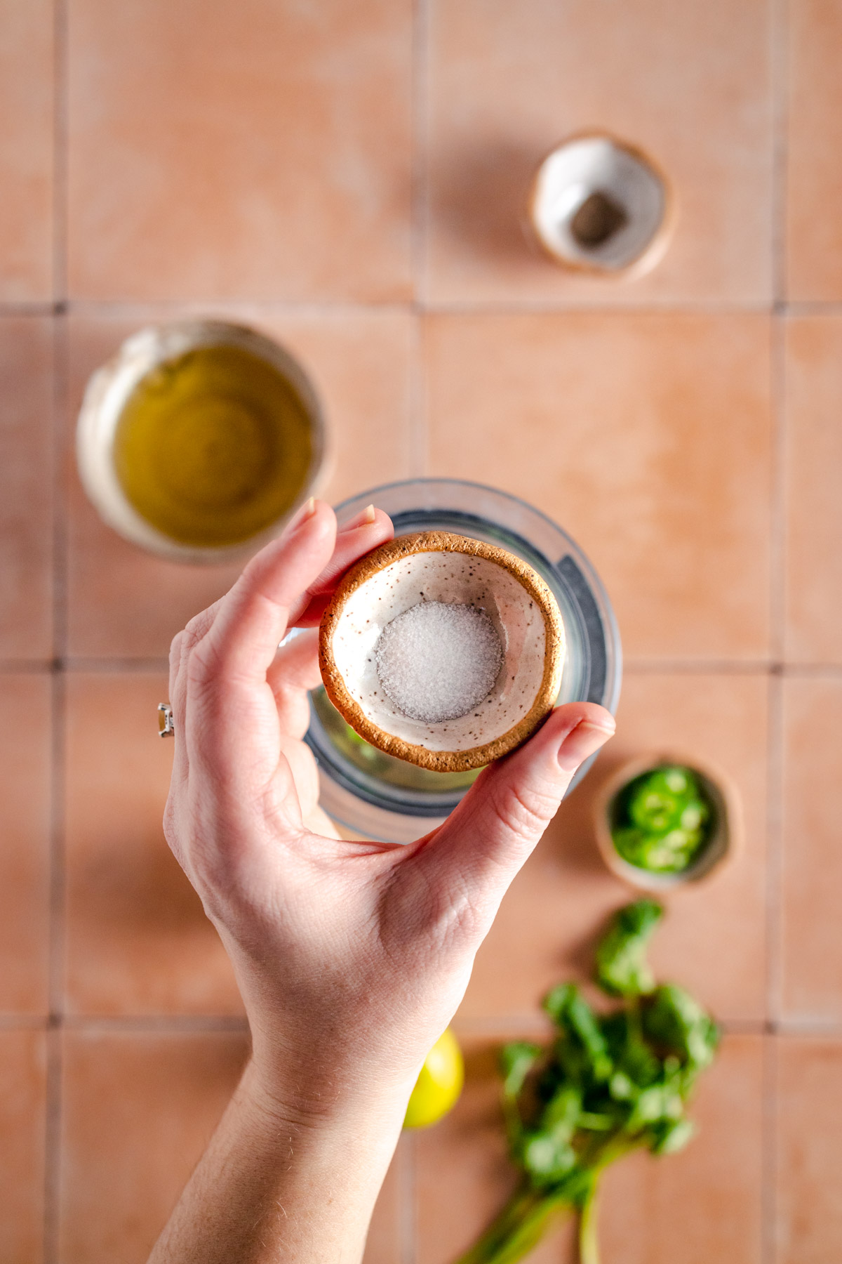 A hand holding a small bowl of salt.