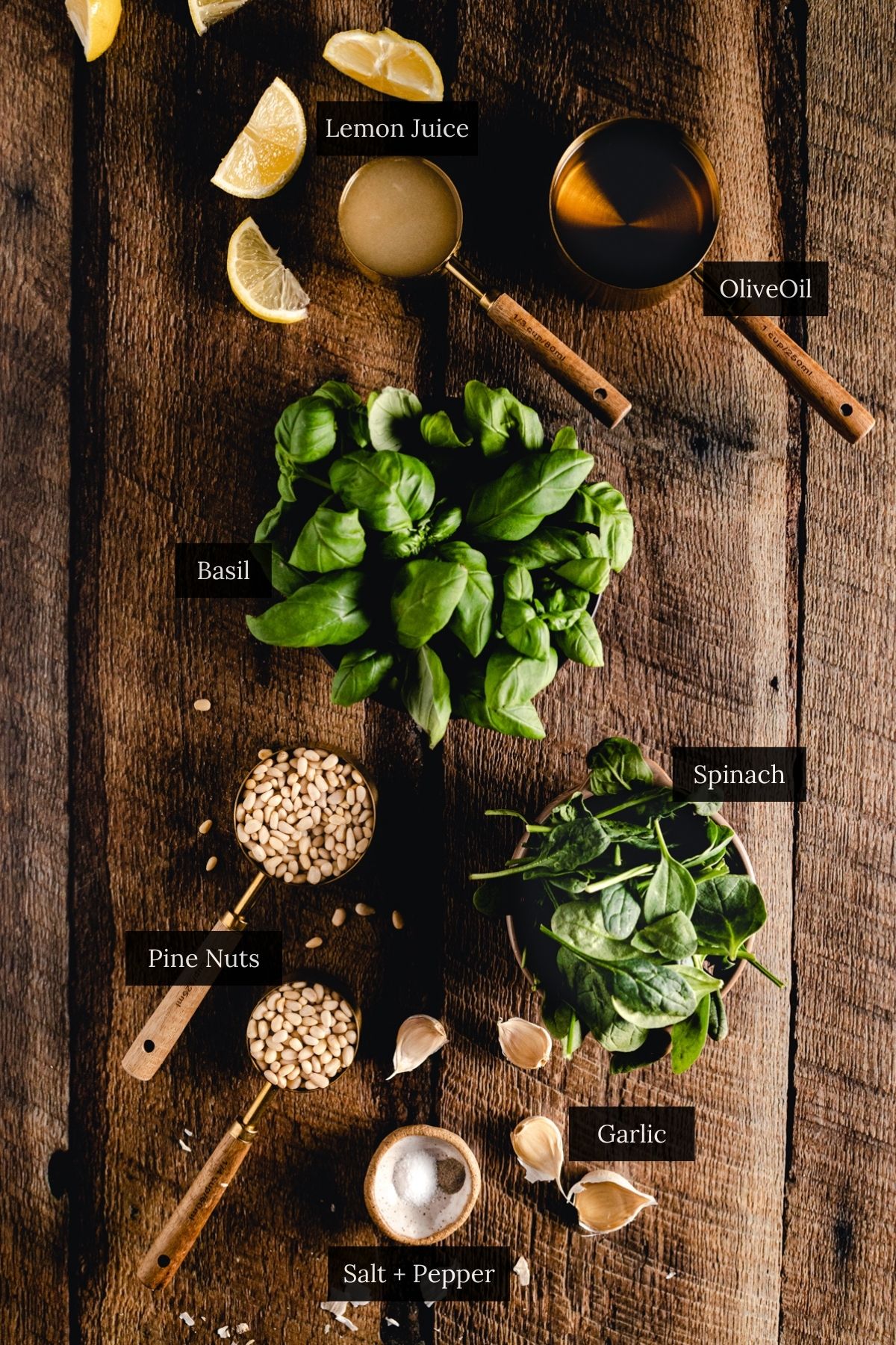 Ingredients for an easy vegan pesto: basil, spinach, garlic, pine nuts, olive oil, lemon juice, salt, and pepper laid out on a wooden surface. The best 5-minute recipe!