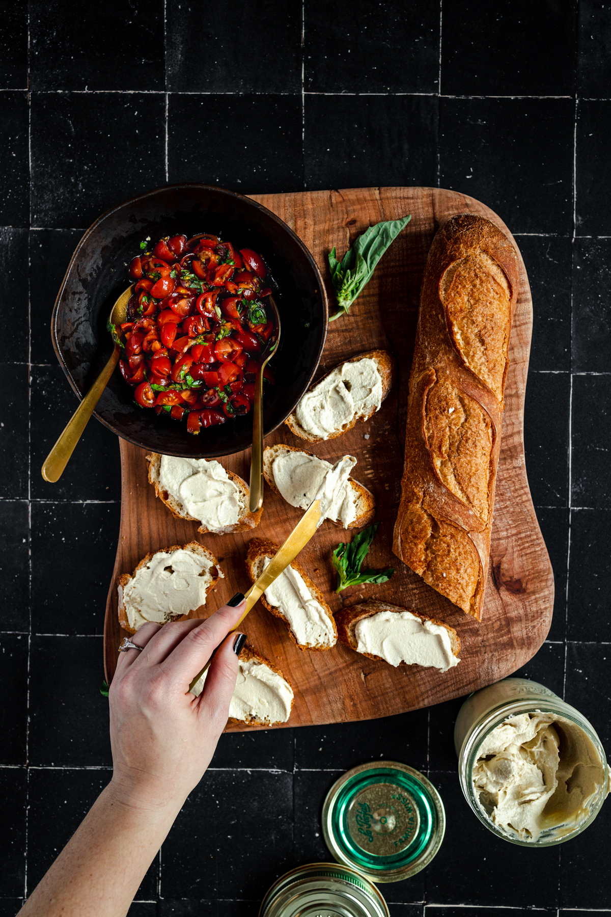 A person is holding bread and a bowl of salsa on a wooden cutting board.