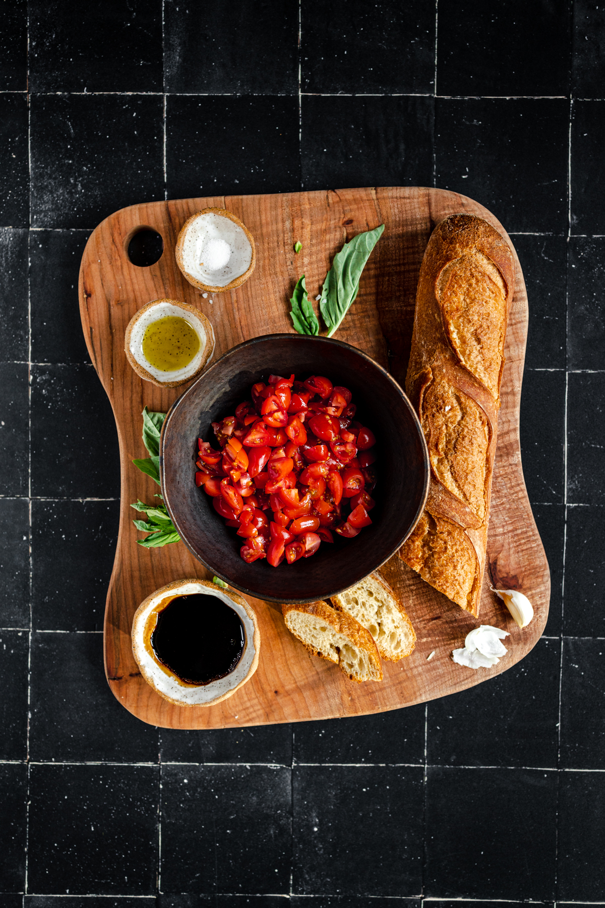 A wooden cutting board with bread and tomatoes on it.