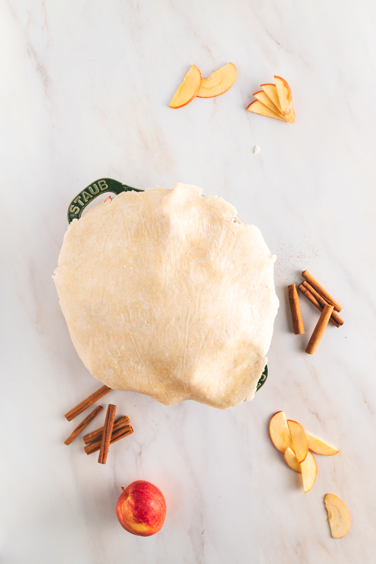 A pie with cinnamon and apples on a marble table.