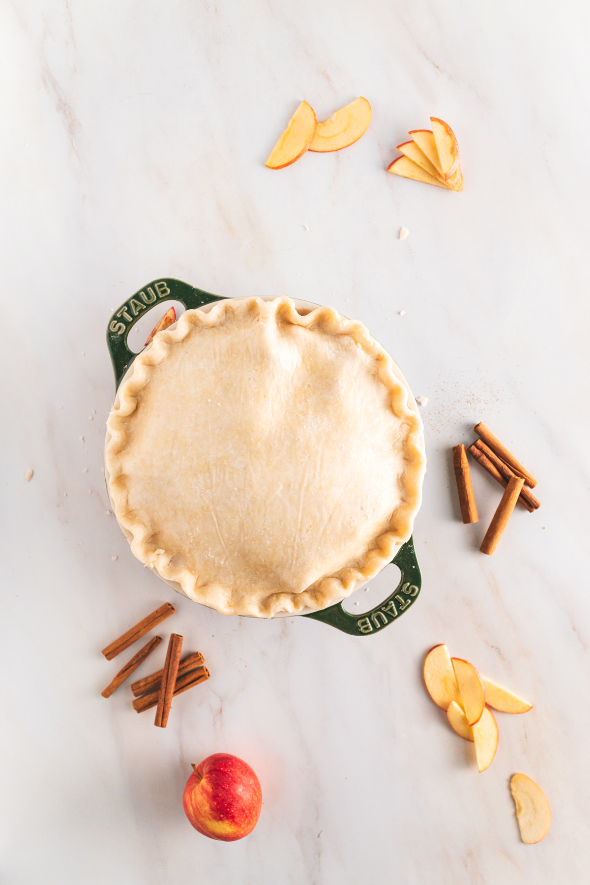 A pie with cinnamon and apples on a marble table.