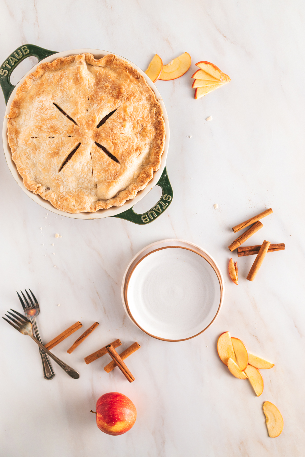 A pie with apples and a fork on a marble table.