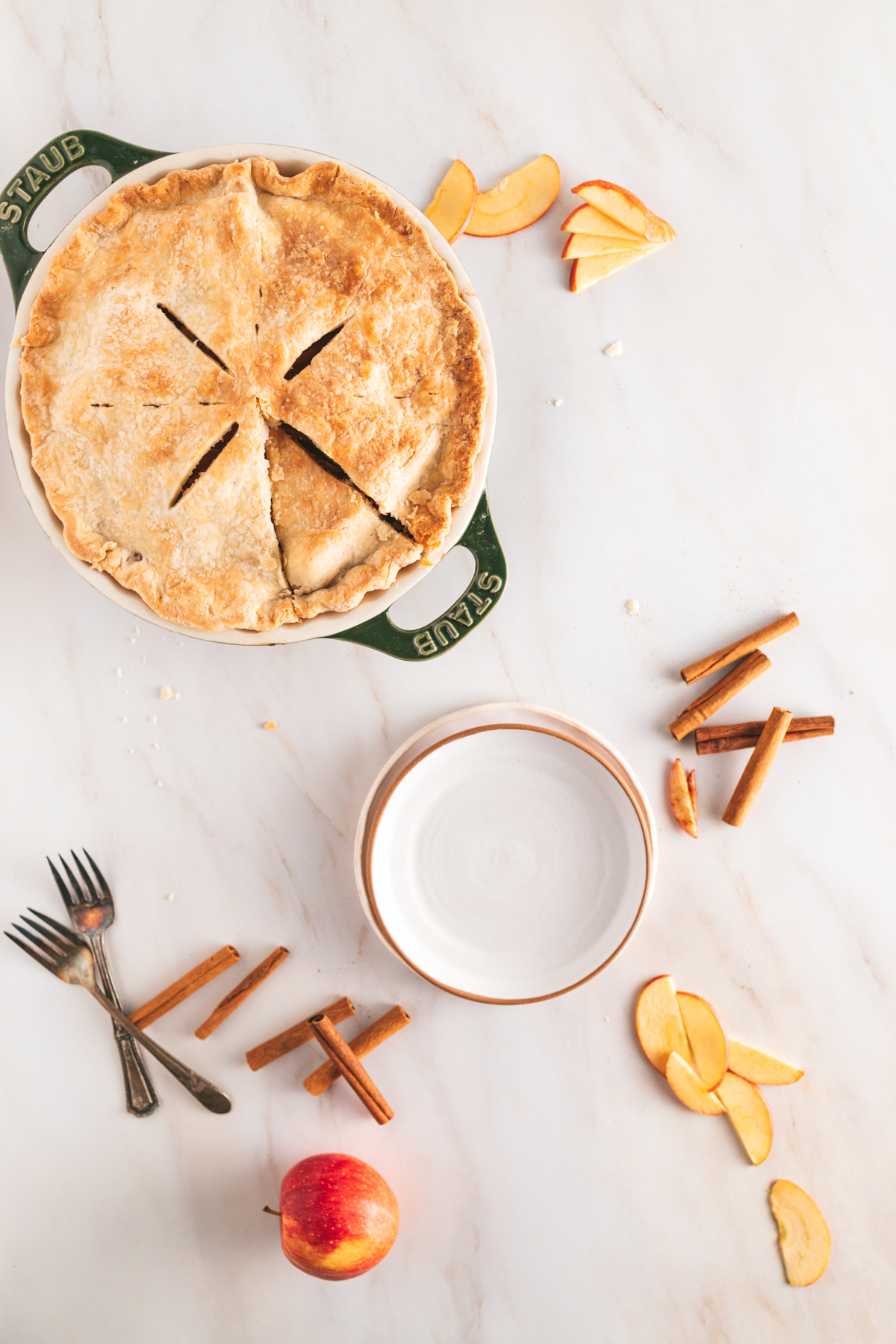 A pie with apples and a fork on a marble table.