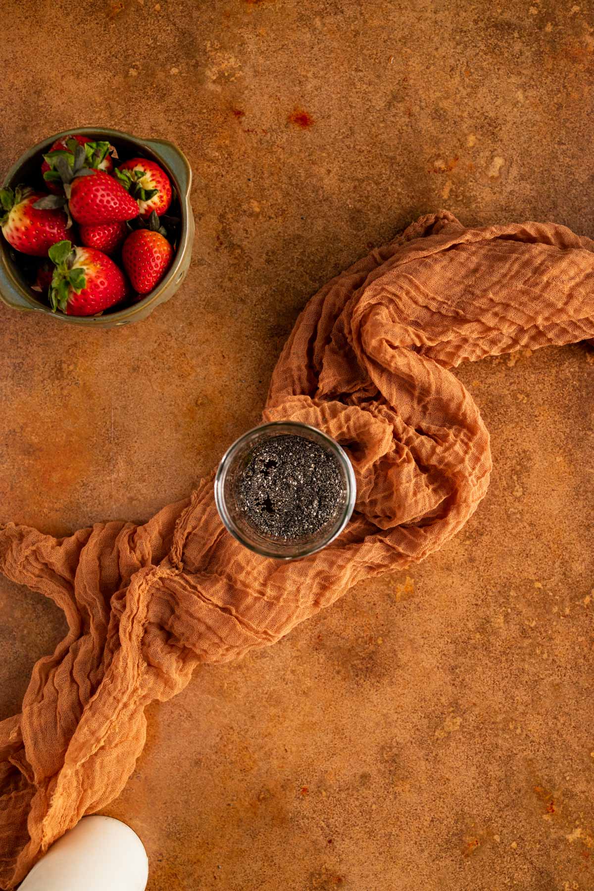 A jar of chia seeds and strawberries on a copper table.