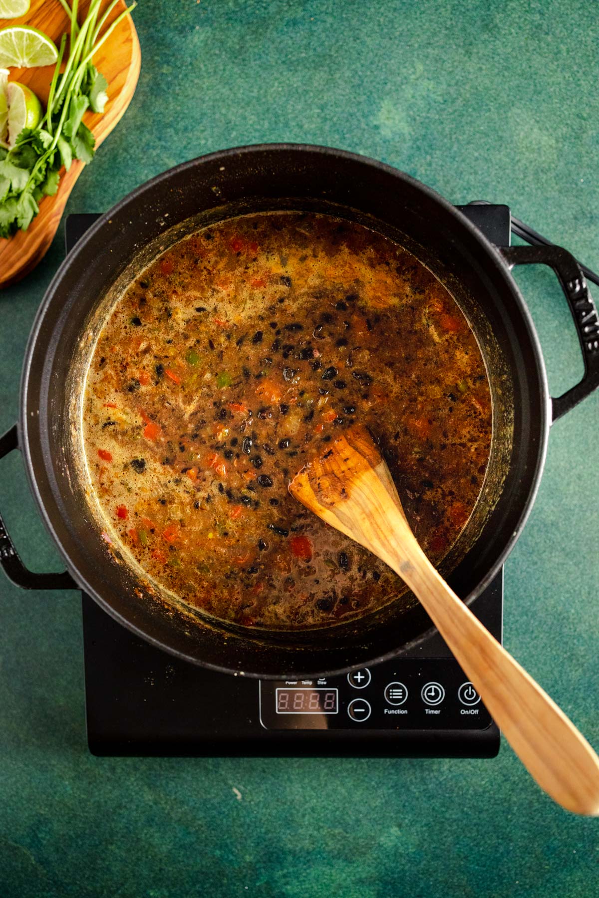 A pot of soup with a wooden spoon next to it.