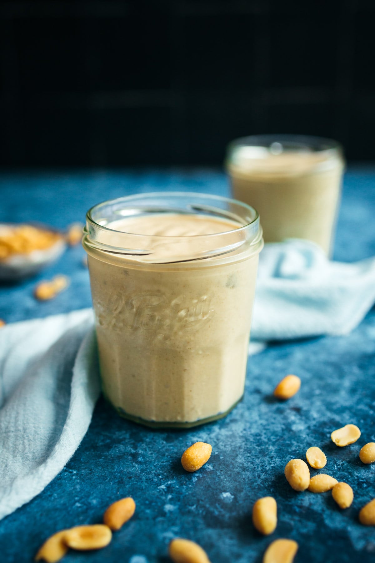 Two jars of peanut butter on a blue table.