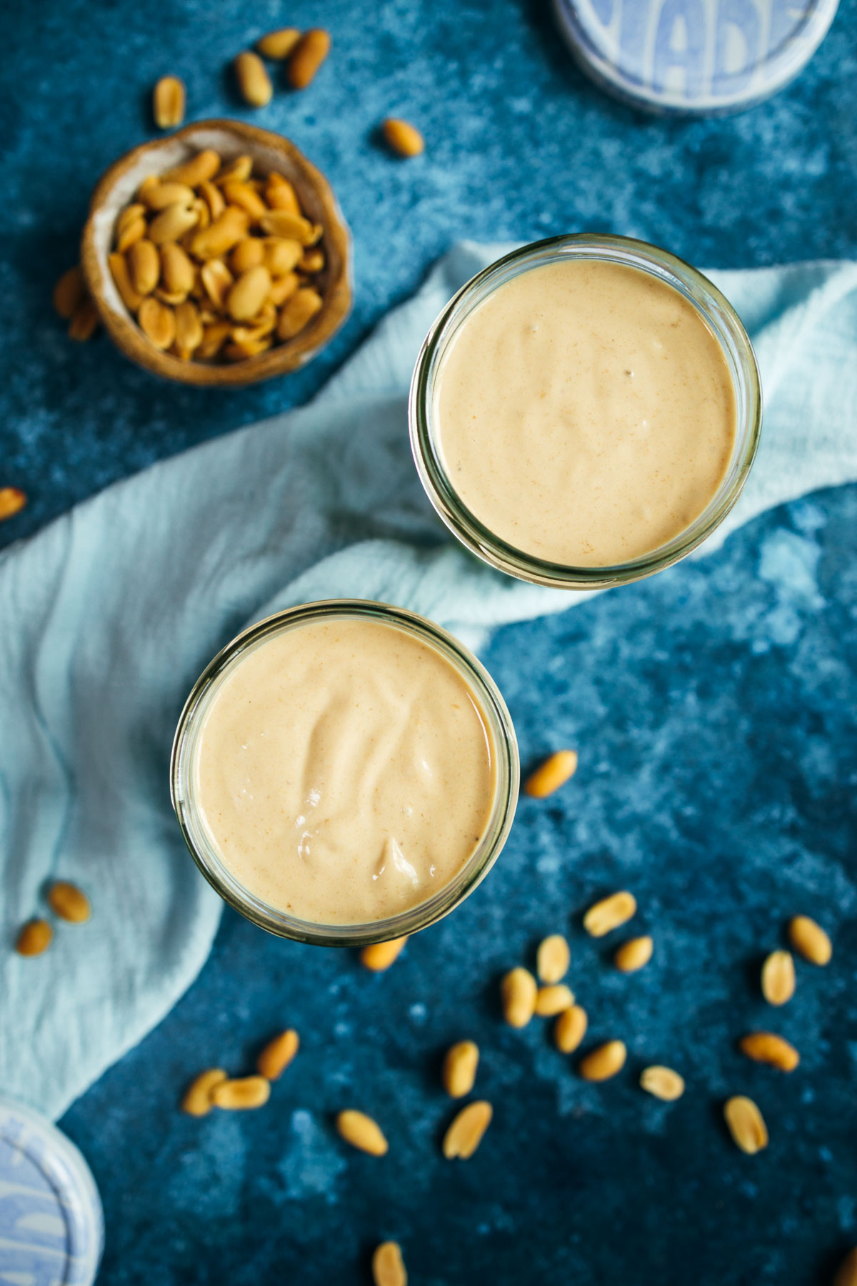 Two jars of peanut butter on a blue background.