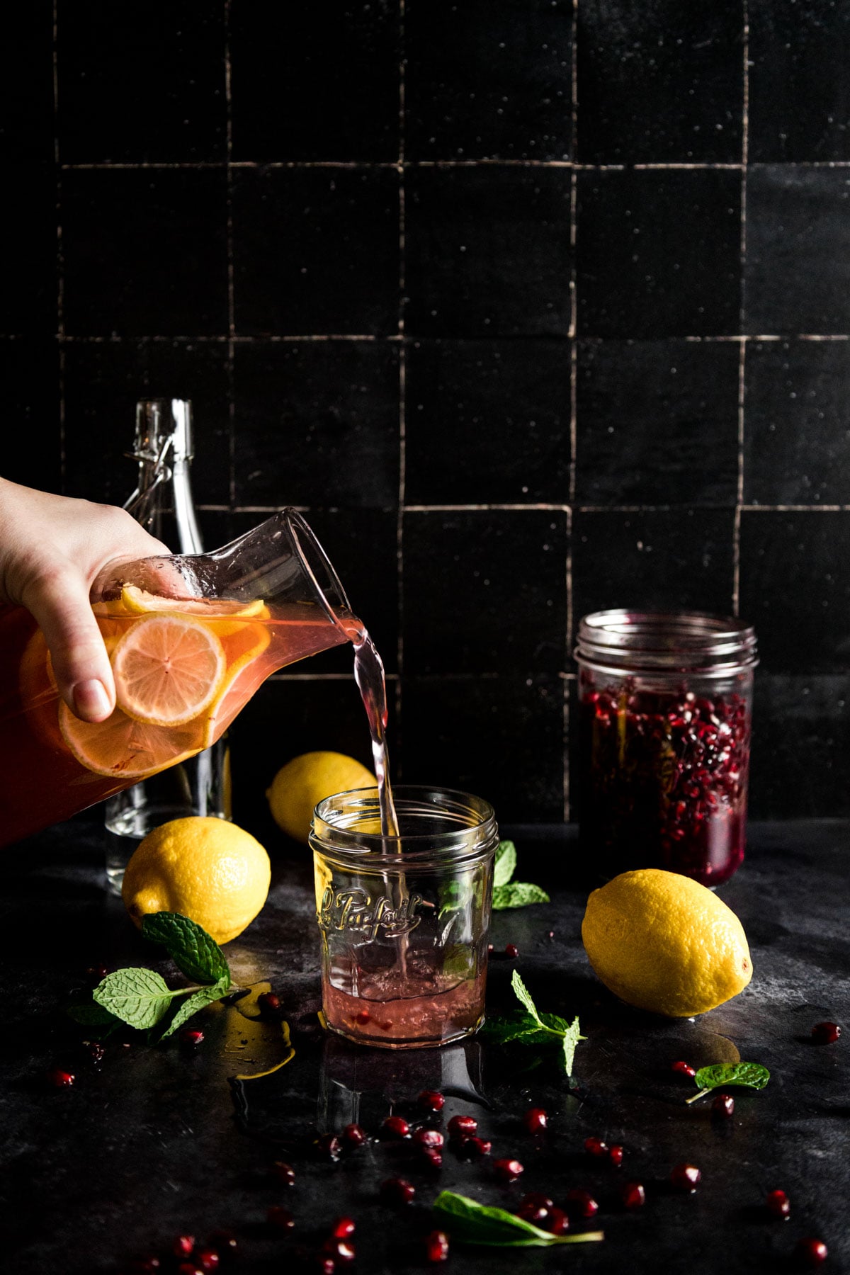 A person pouring pomegranate juice into a jar.