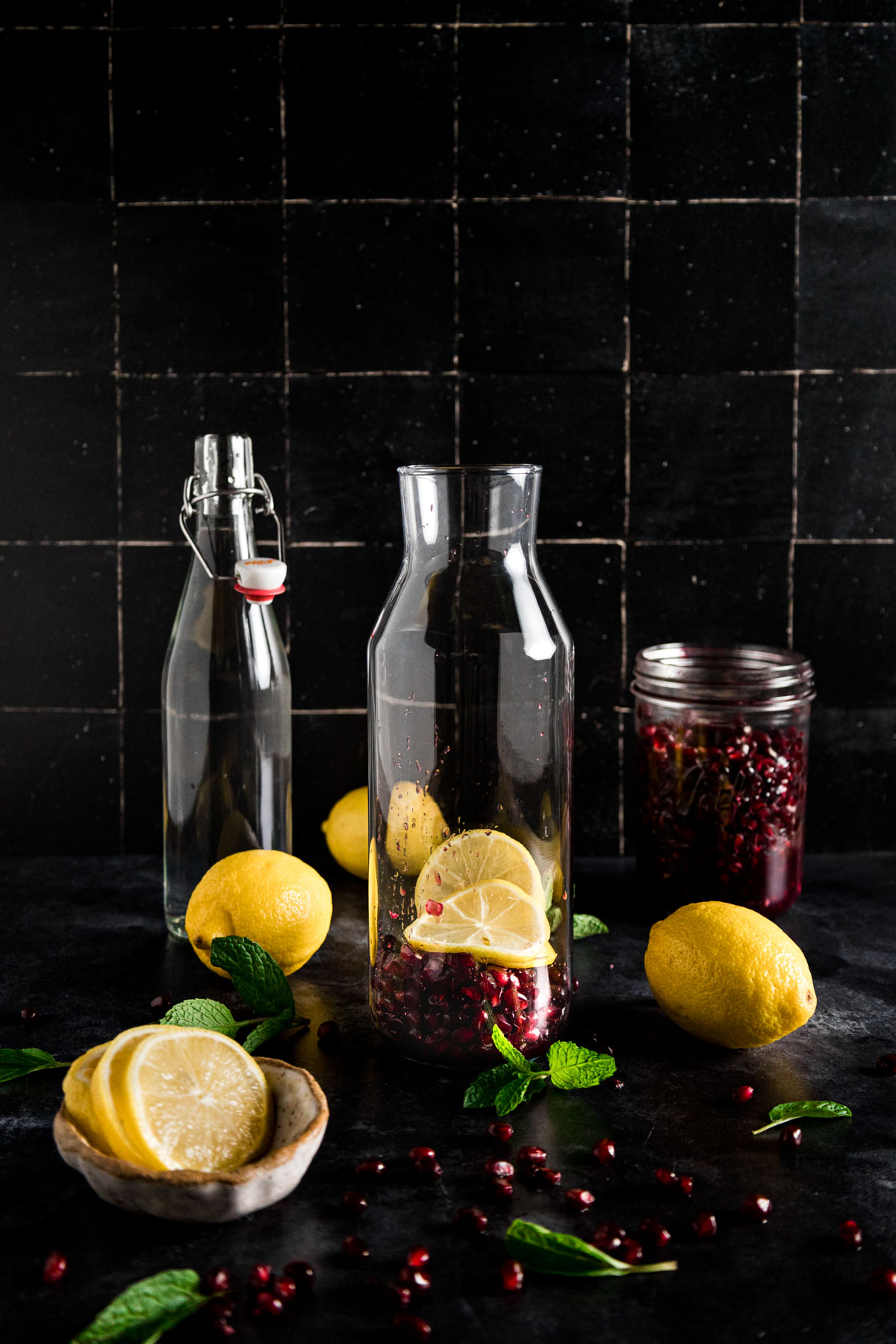 A glass jar with lemons, pomegranates and mint.
