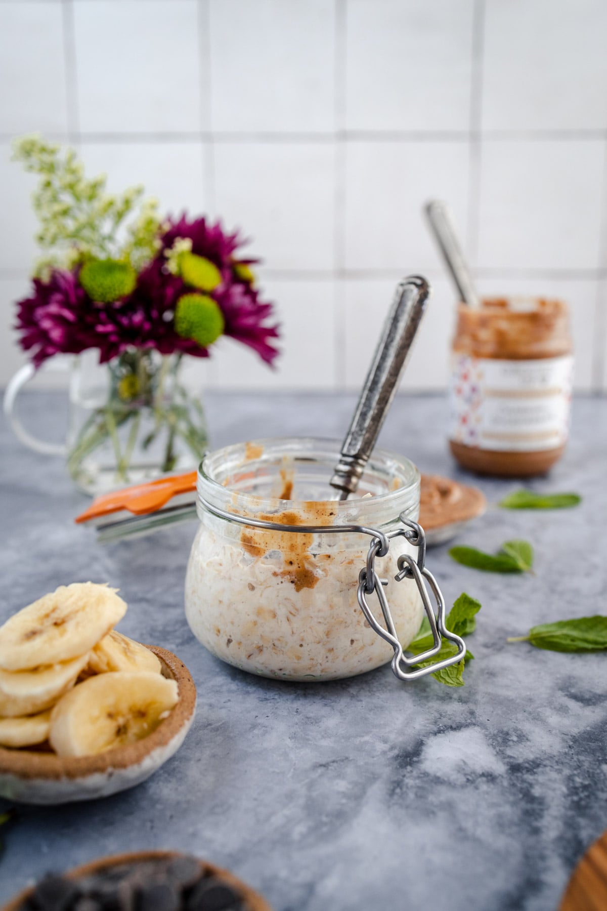 Jar of overnight oats with peanut butter and banana slices on a kitchen counter.