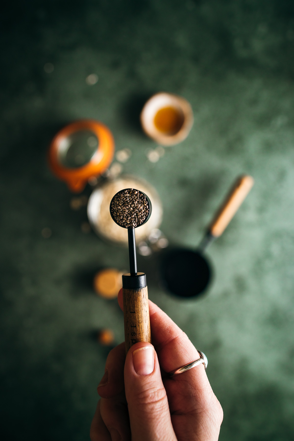 Hand holding a portafilter with freshly ground coffee on a blurred background with coffee-making tools.