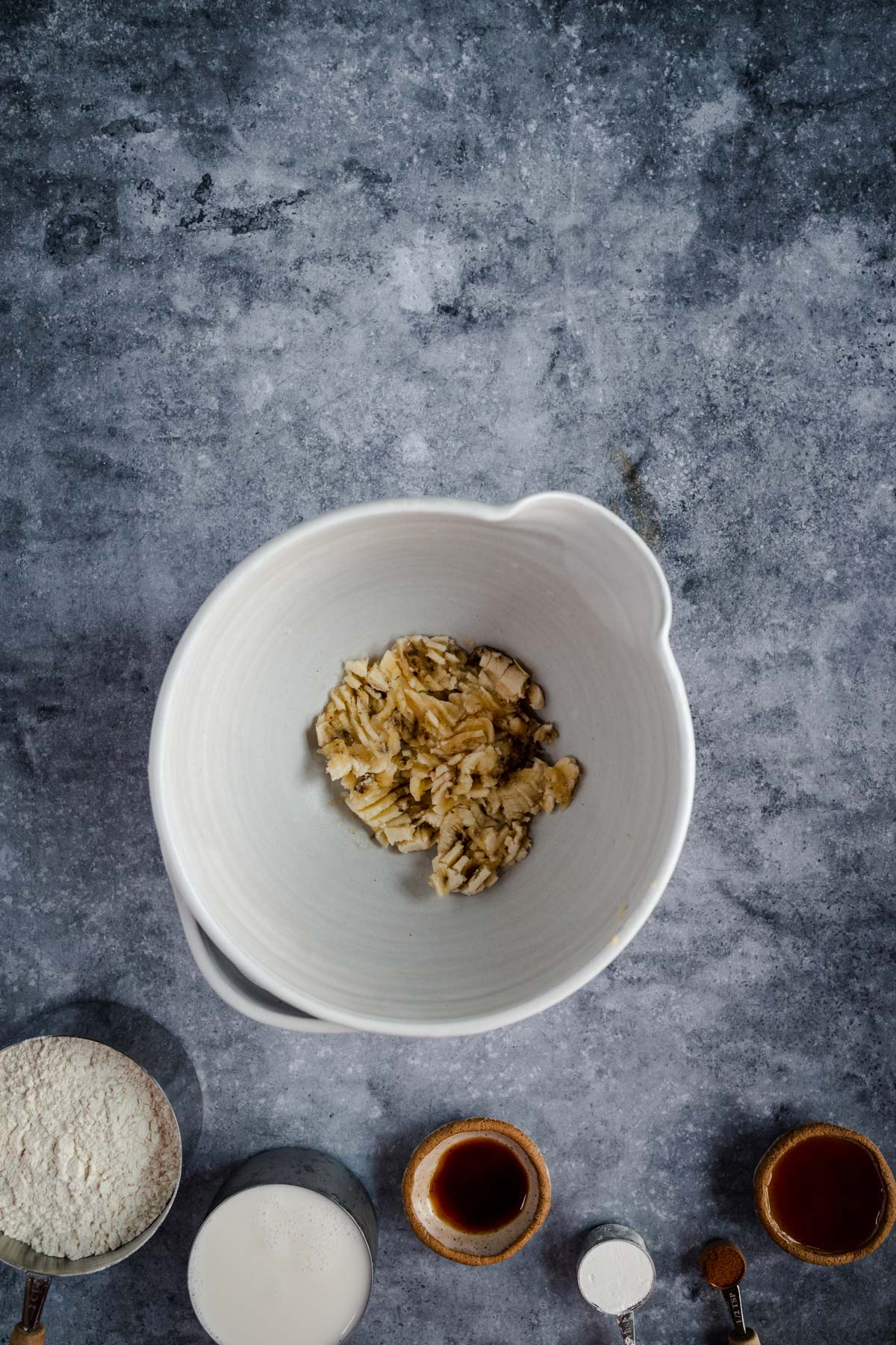 Various ingredients arranged on a textured surface with a bowl at the center containing a scoop of oatmeal.