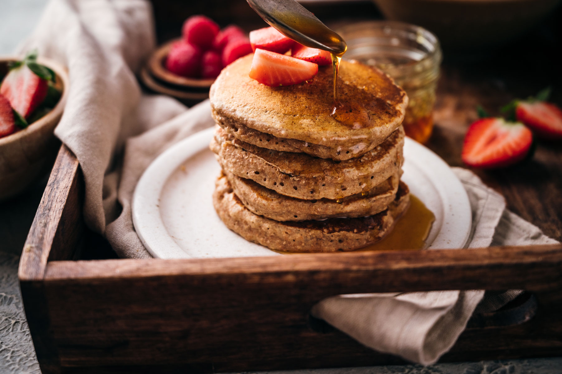 Drizzling maple syrup on top of vegan pancakes.