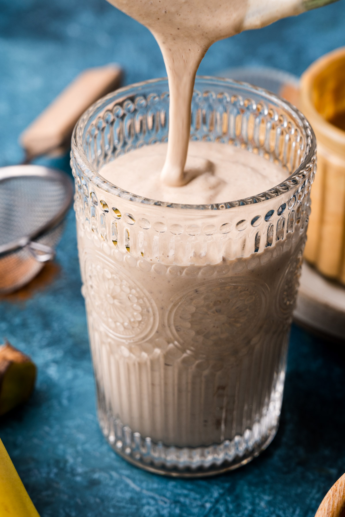 Creamy smoothie being poured into a glass.