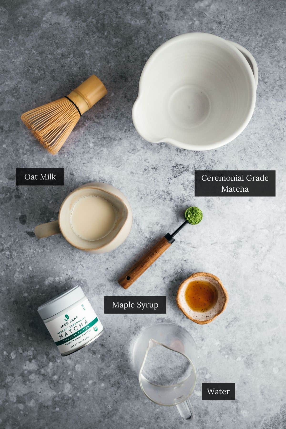 Flat lay of matcha latte ingredients on a gray surface.