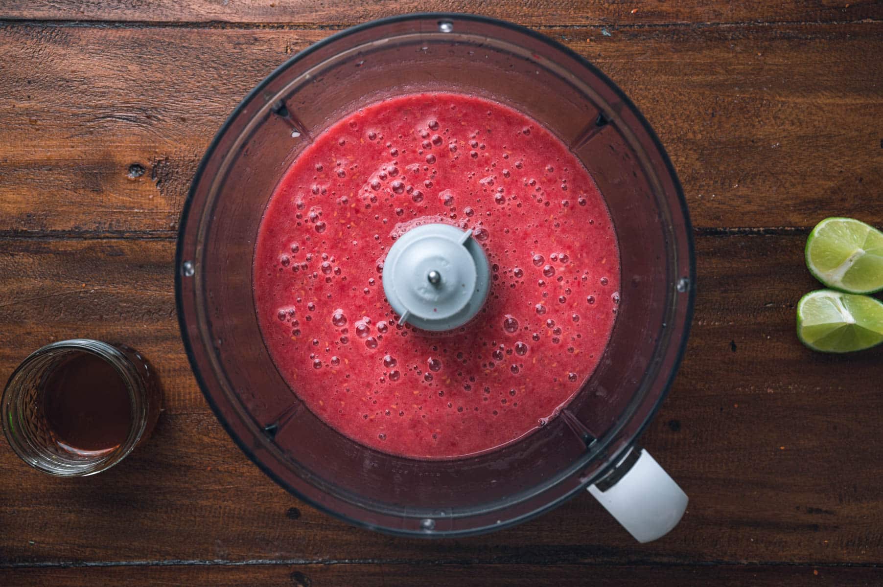 A food processor filled with blended raspberry sorbet.