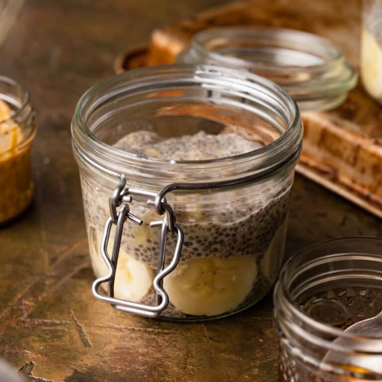 A glass jar brimming with banana chia pudding, featuring delightful slices of fresh banana, rests elegantly on a wooden surface.