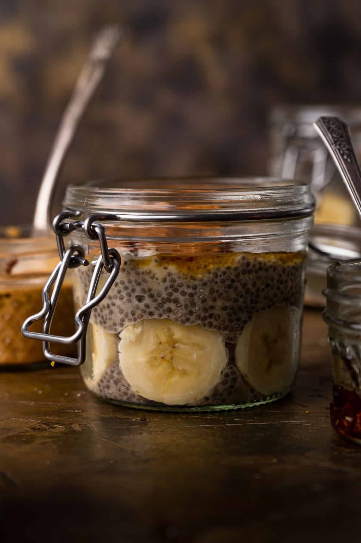 A glass jar filled with chia pudding and banana slices, sealed with a metal clasp lid.