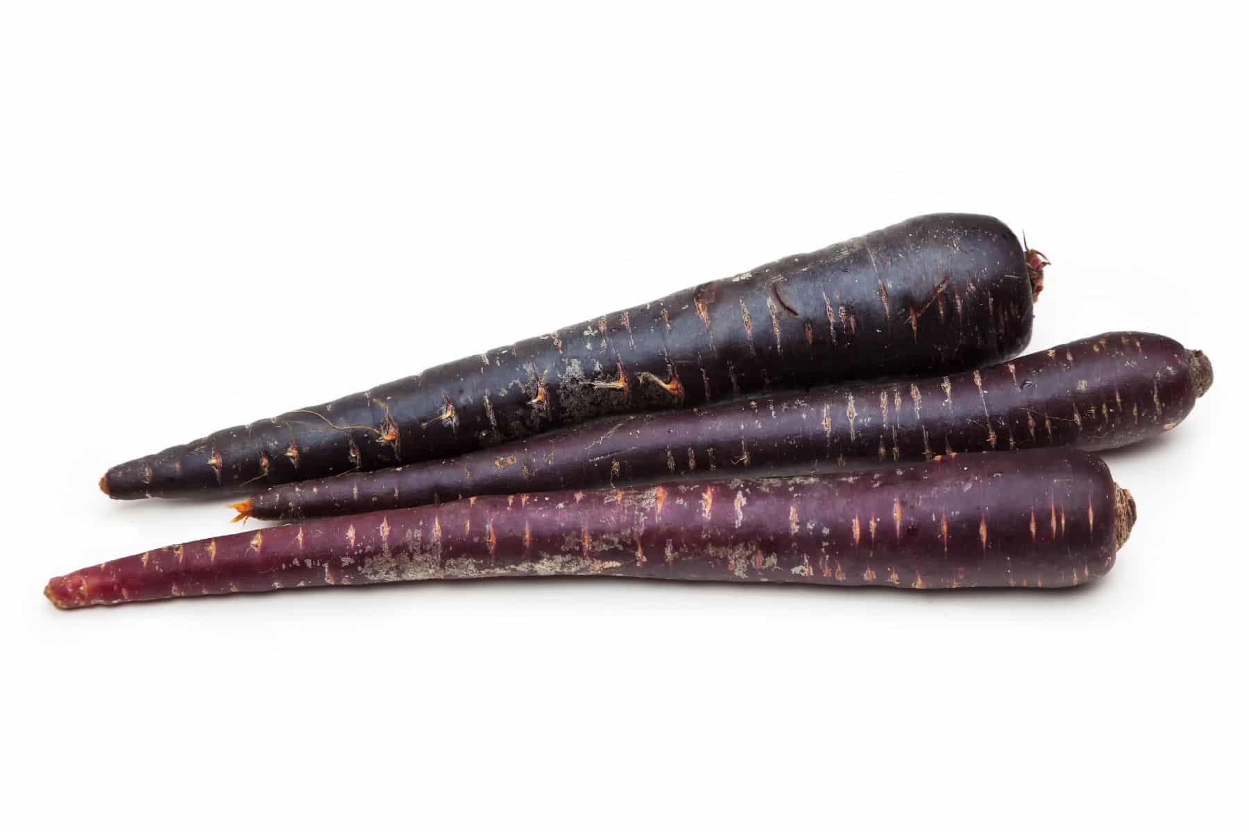 Three purple carrots lie on a white background.