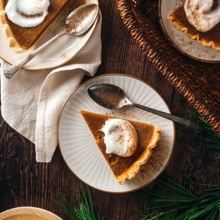 A slice of no egg pumpkin pie with whipped cream on a white plate.