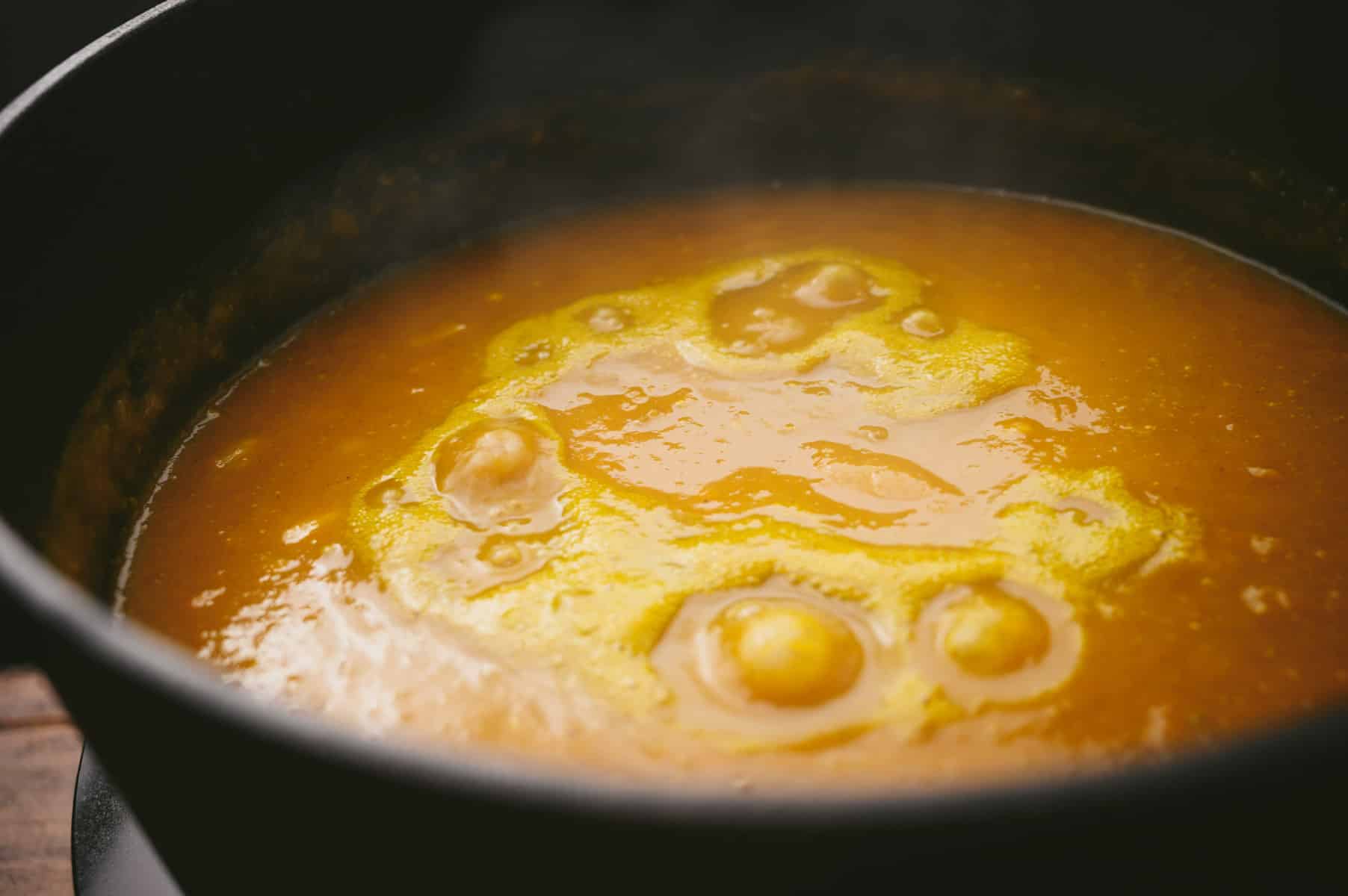 A black pot of pumpkin soup boiling.