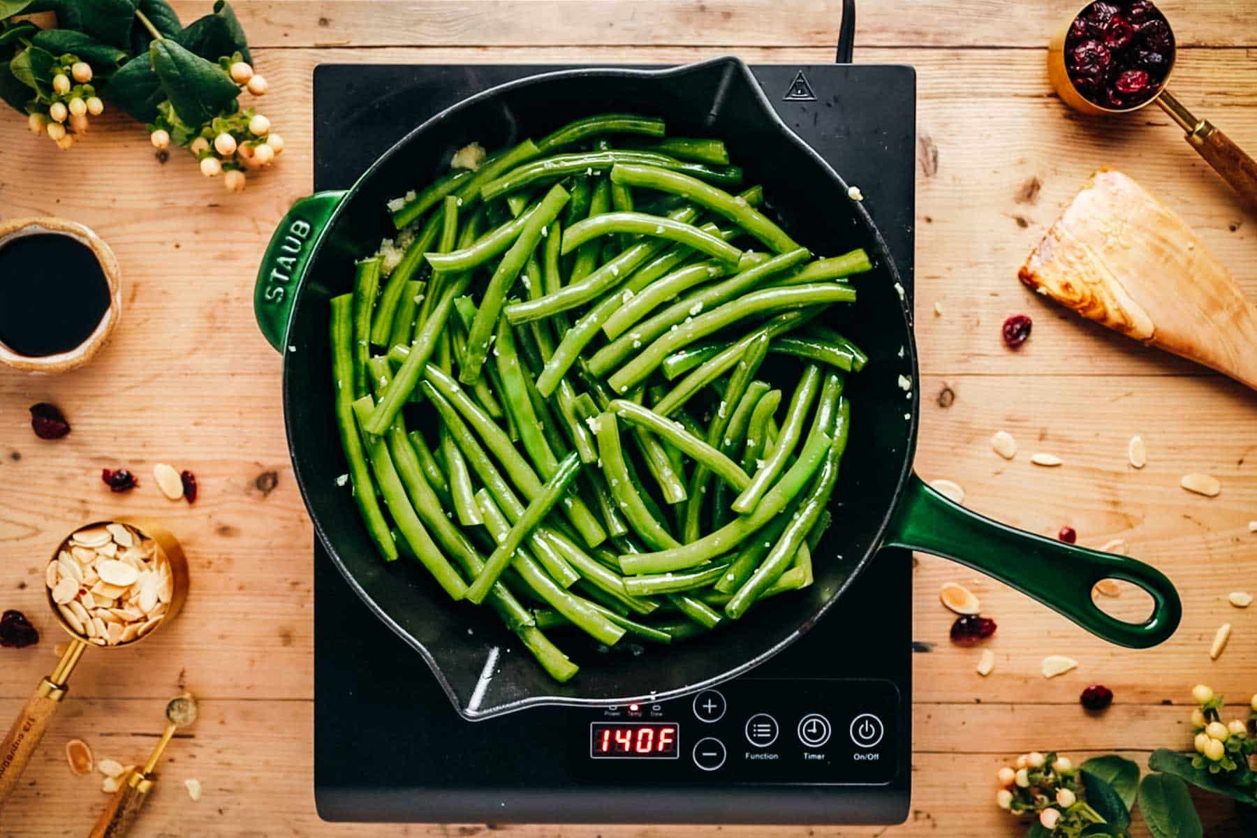Green beans cooking in a skillet on an induction stove.