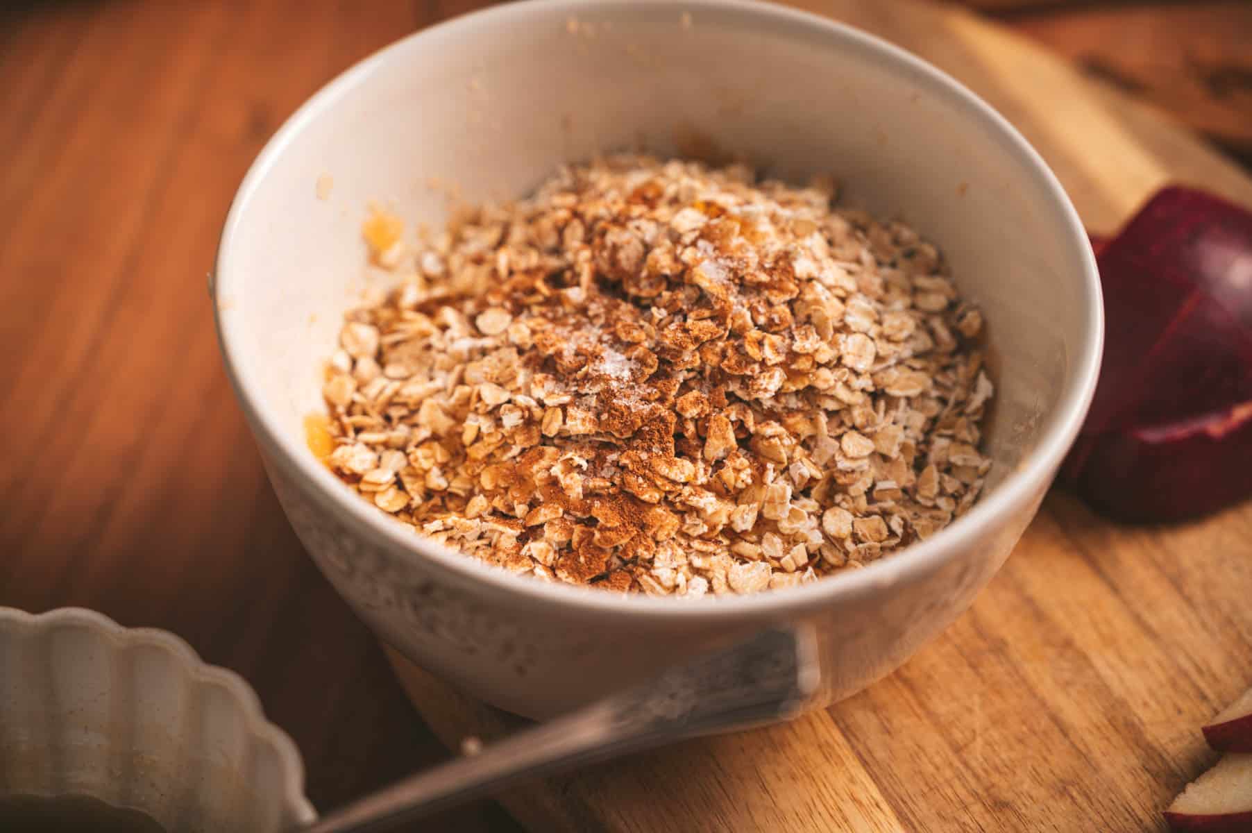 Oats, cinnamon, and maple syrup in a ceramic bowl.