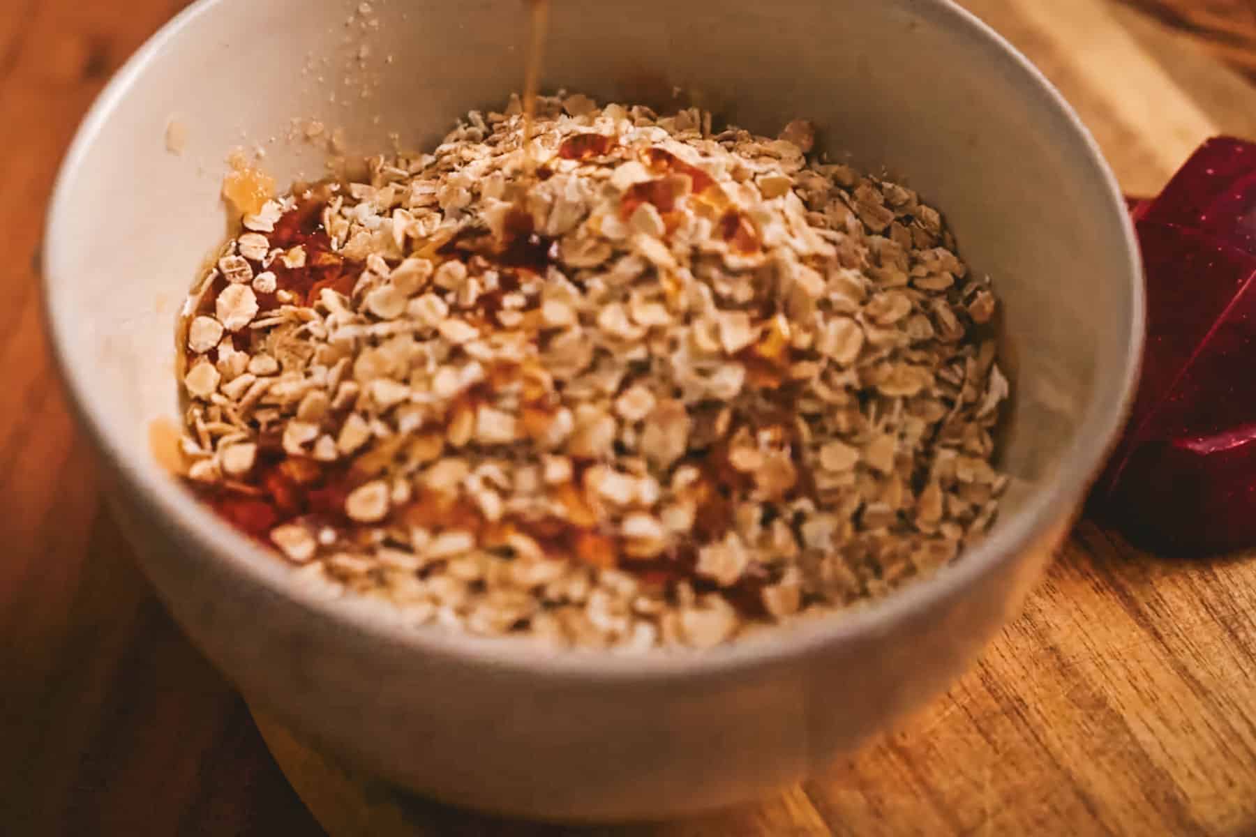 Drizzling maple syrup over rolled oats.