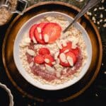 Bowl of single serve oatmeal for one with sliced strawberries on top.