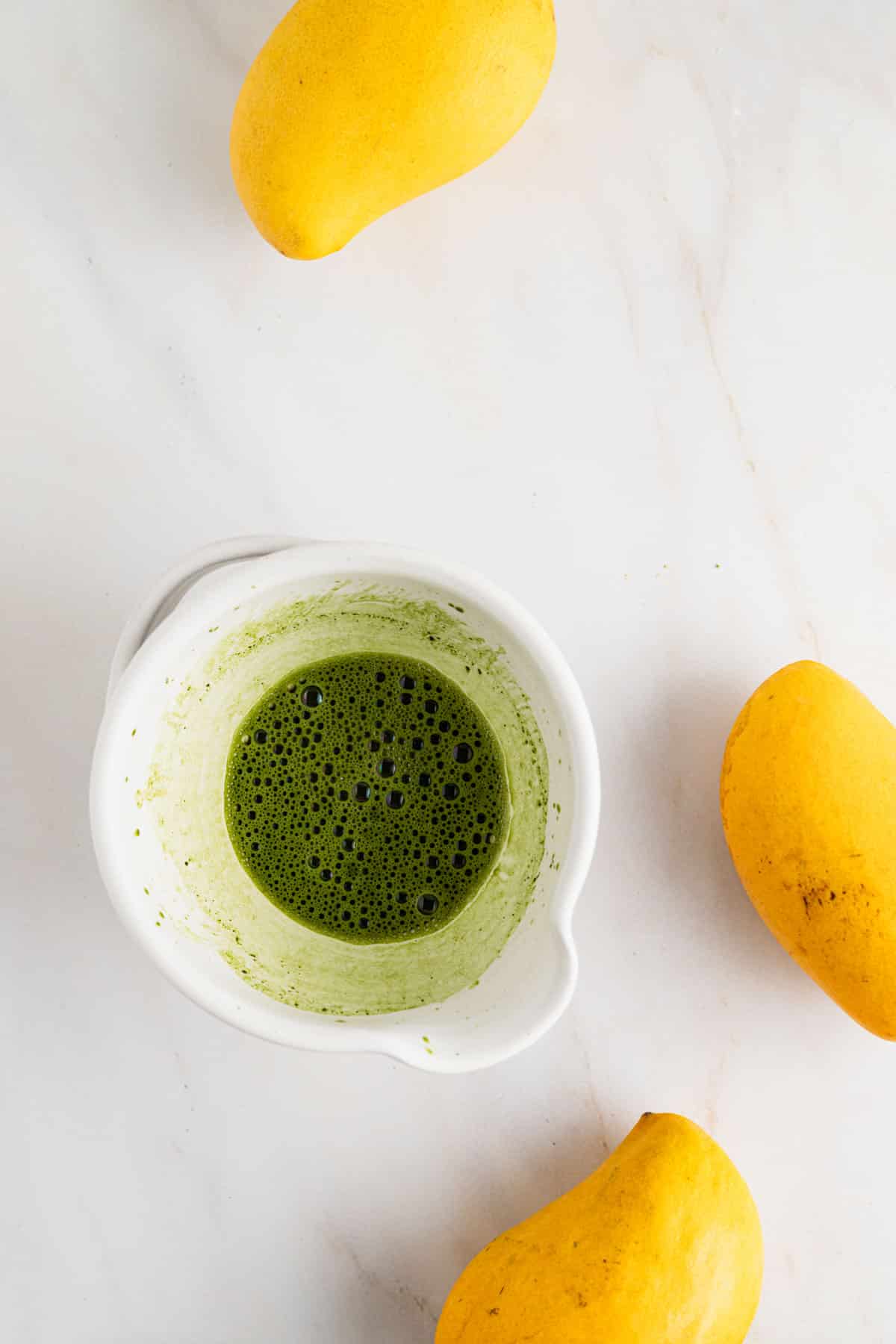Mixing vibrant green matcha with hot water and a bamboo whisk.