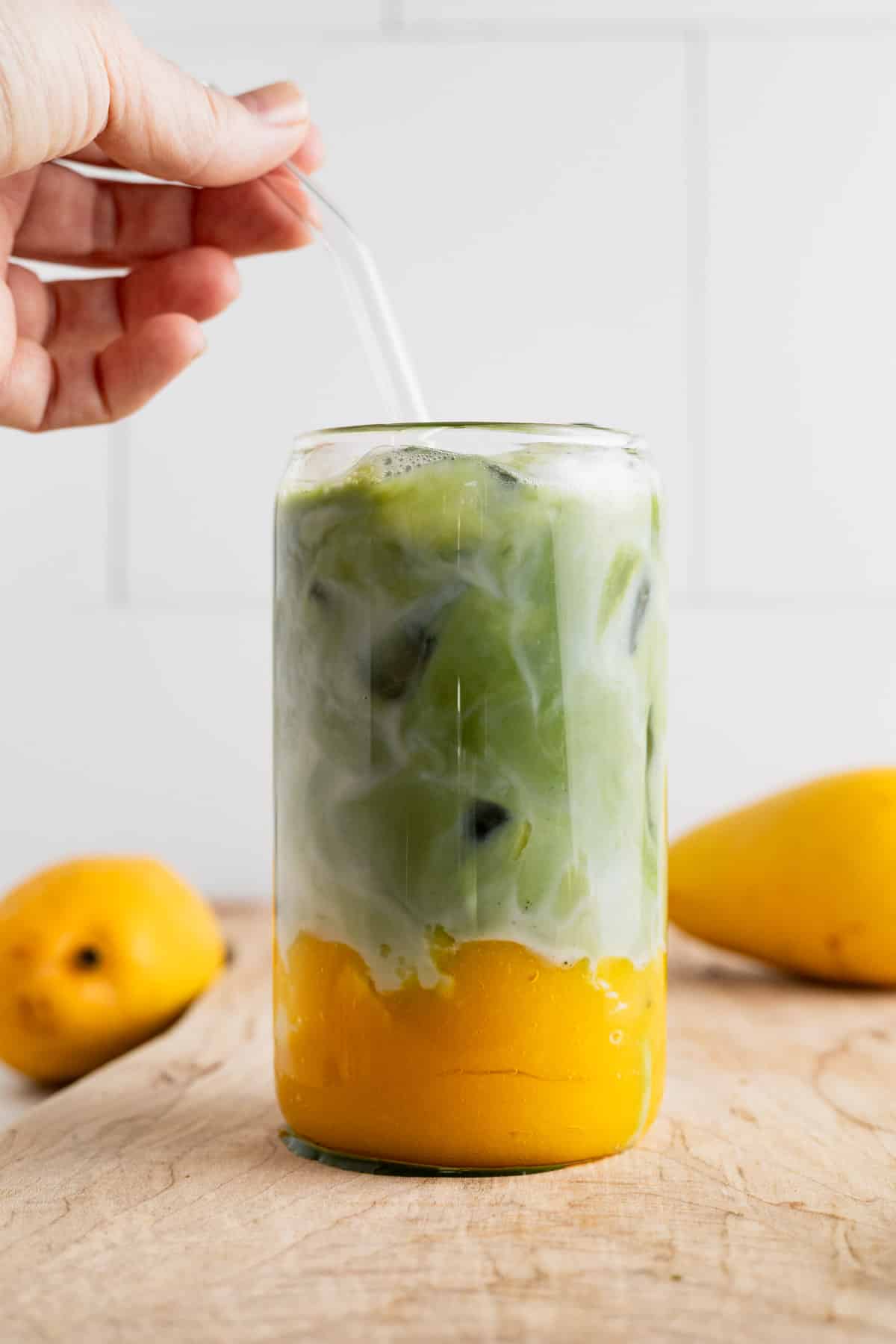 Glass straw being added to a cup of homemade mango matcha.