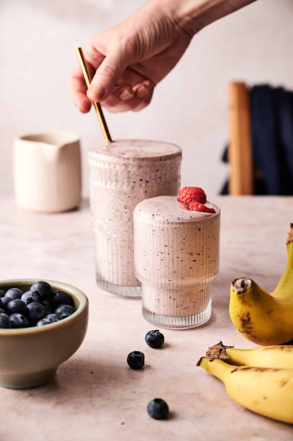 Woman placing a straw in a glass filled with smoothie.