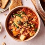Orzo veggie soup in a bowl being served with toast.