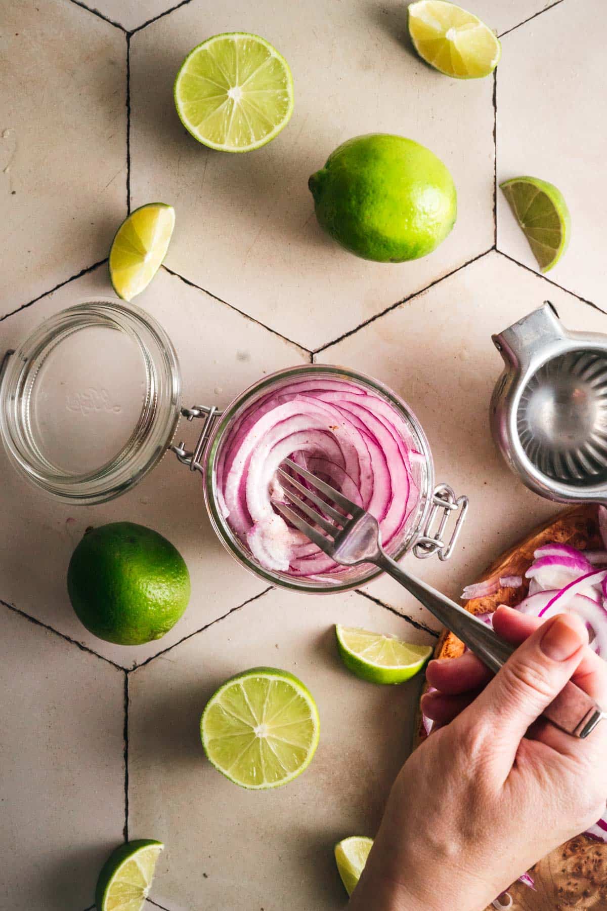 Glass jar filled with thin sliced red onion and lime juice.
