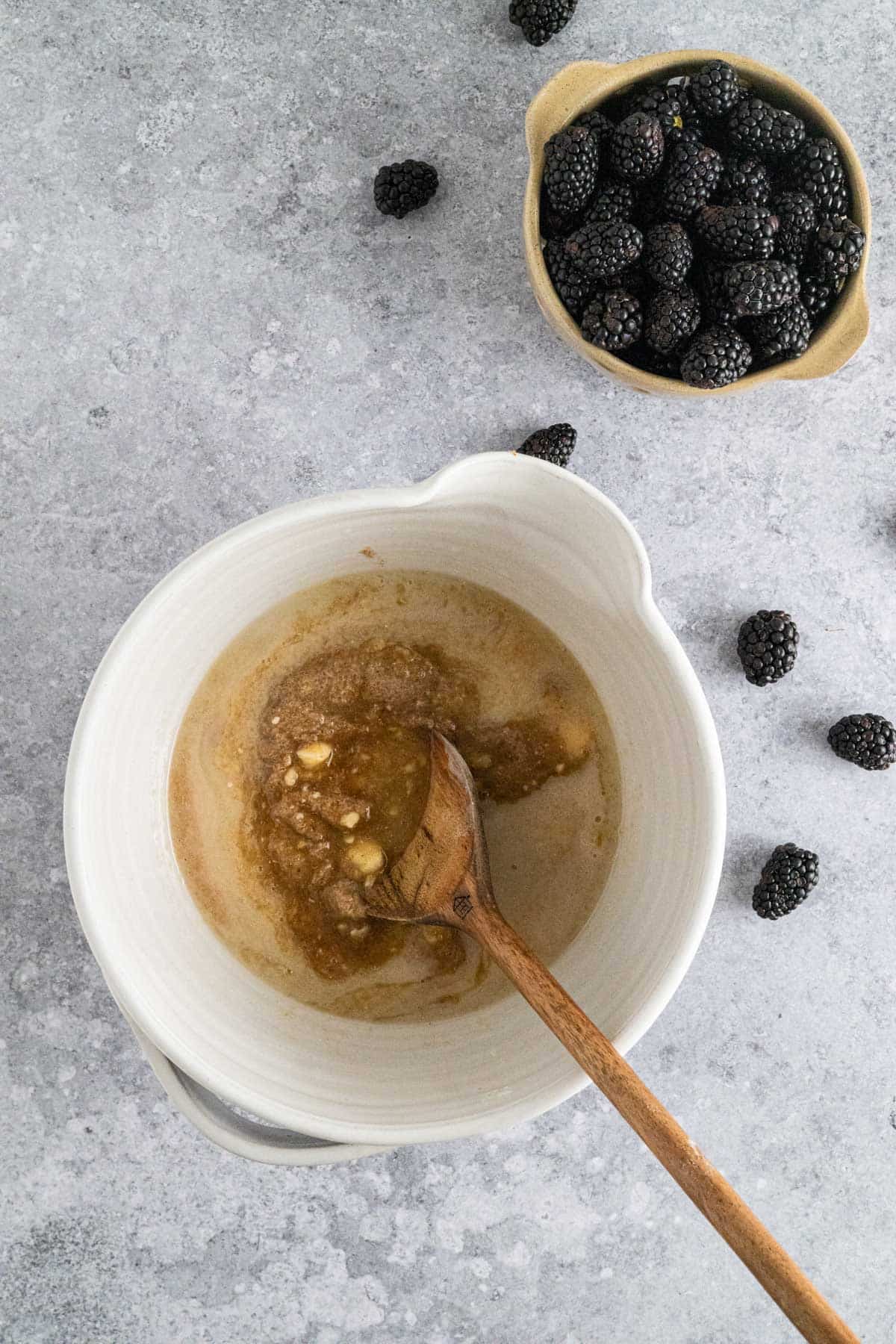 Stirring wet ingredients for blackberry banana muffins with a wooden spoon.