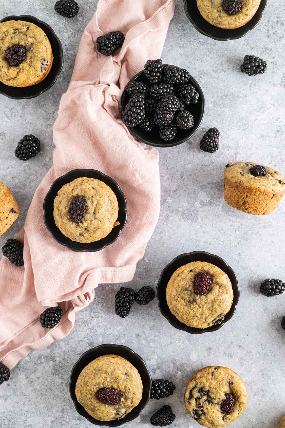 Baked blackberry banana muffins on a stone counter.