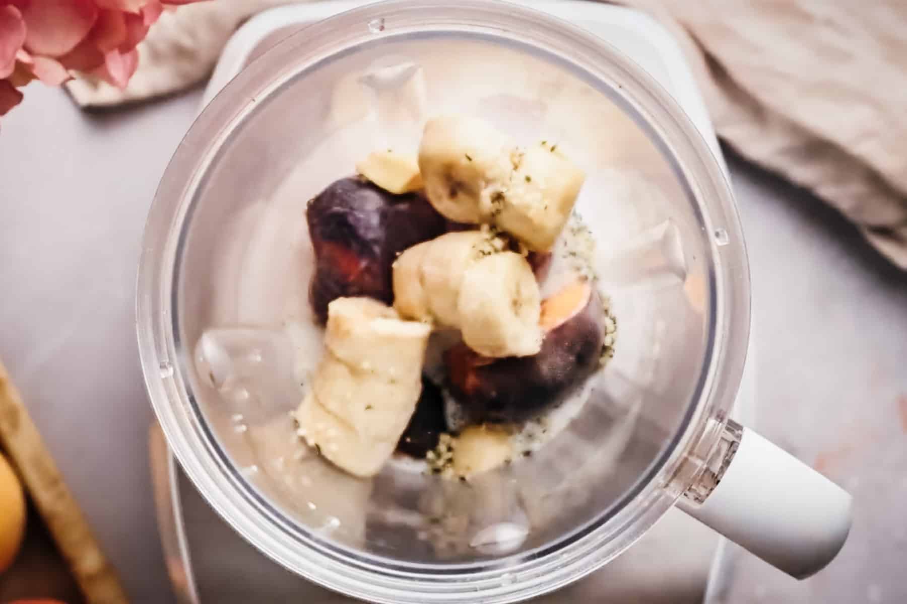 All of the ingredients for peach banana smoothie in a blender pitcher.