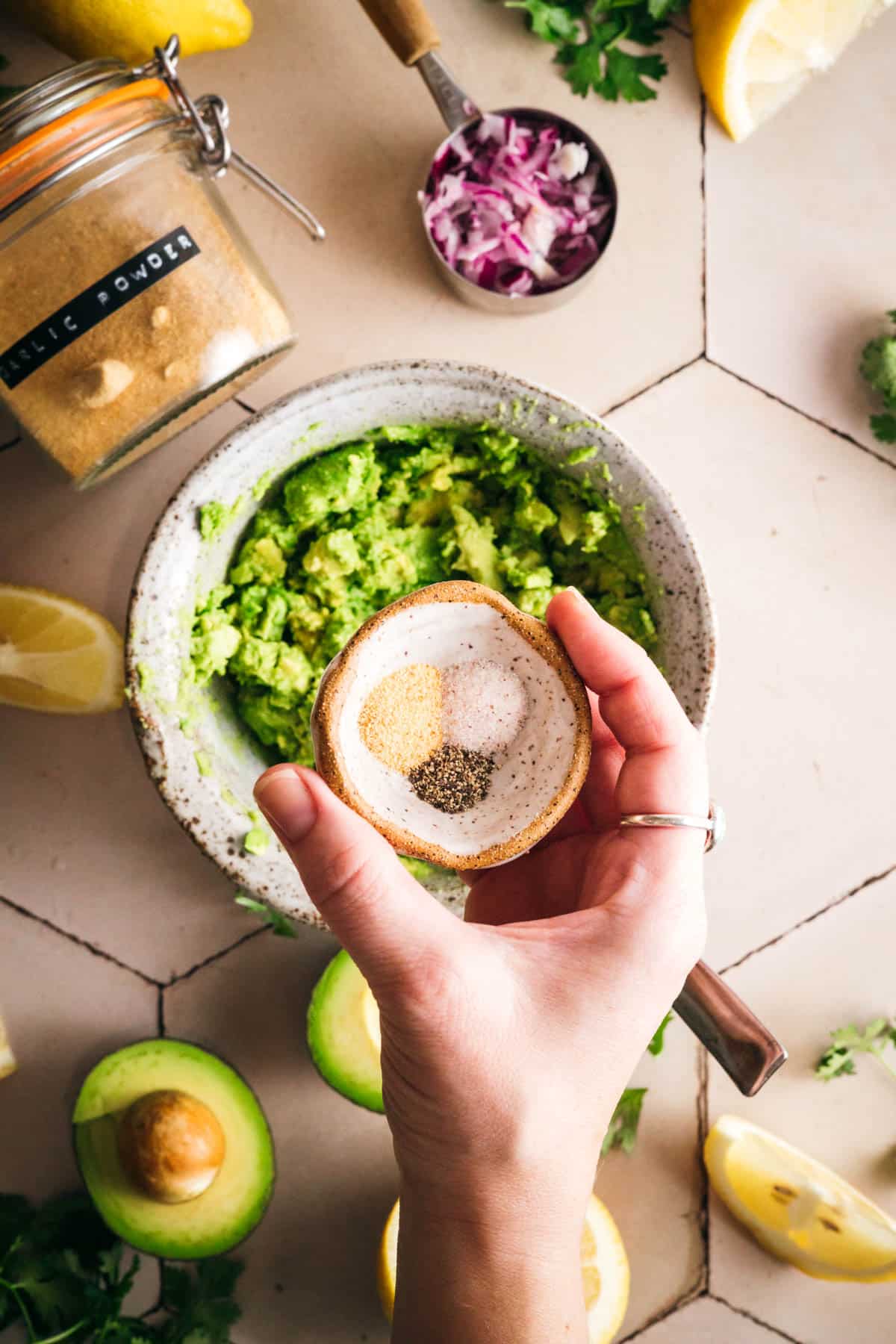 Adding spices to mashed avocado.