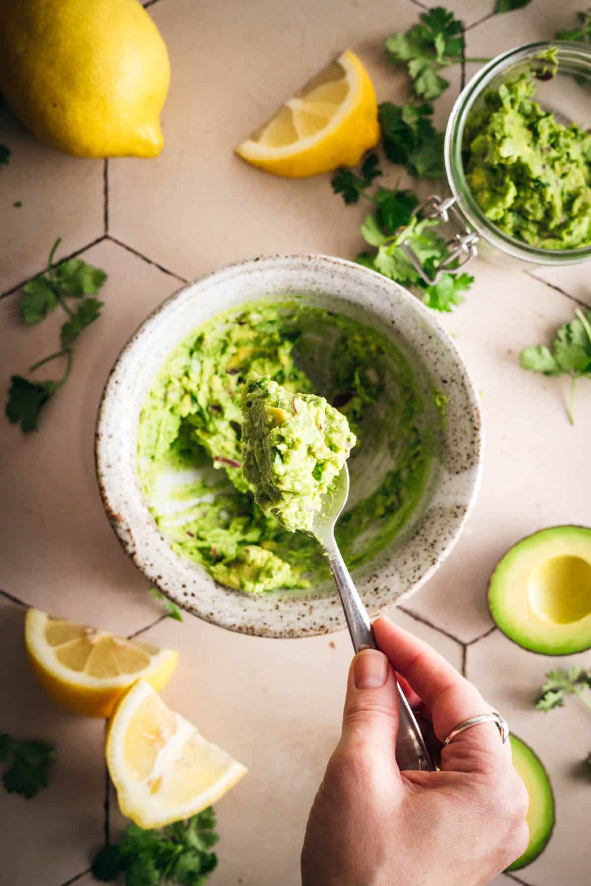 Scooping homemade lemon guacamole into a Le Parfait jar.