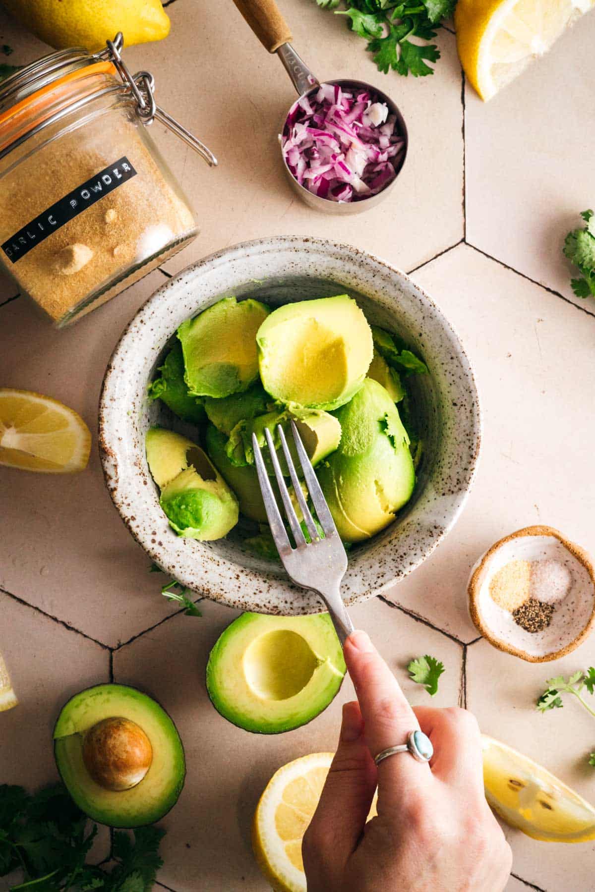 Mashing fresh avocado in a bowl for homemade guacamole.