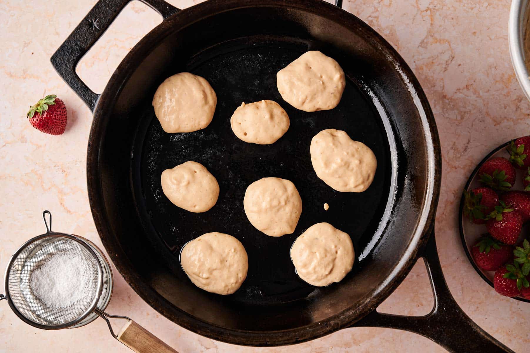 Cooking mini vegan pancakes in a cast iron skillet.