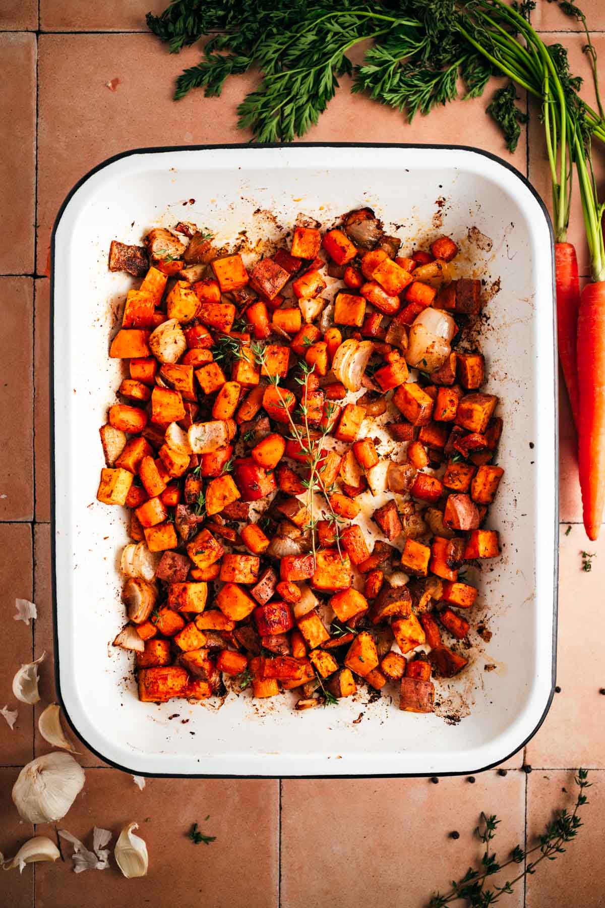 Roasted sweet potatoes and carrots in an enamel baking tray.