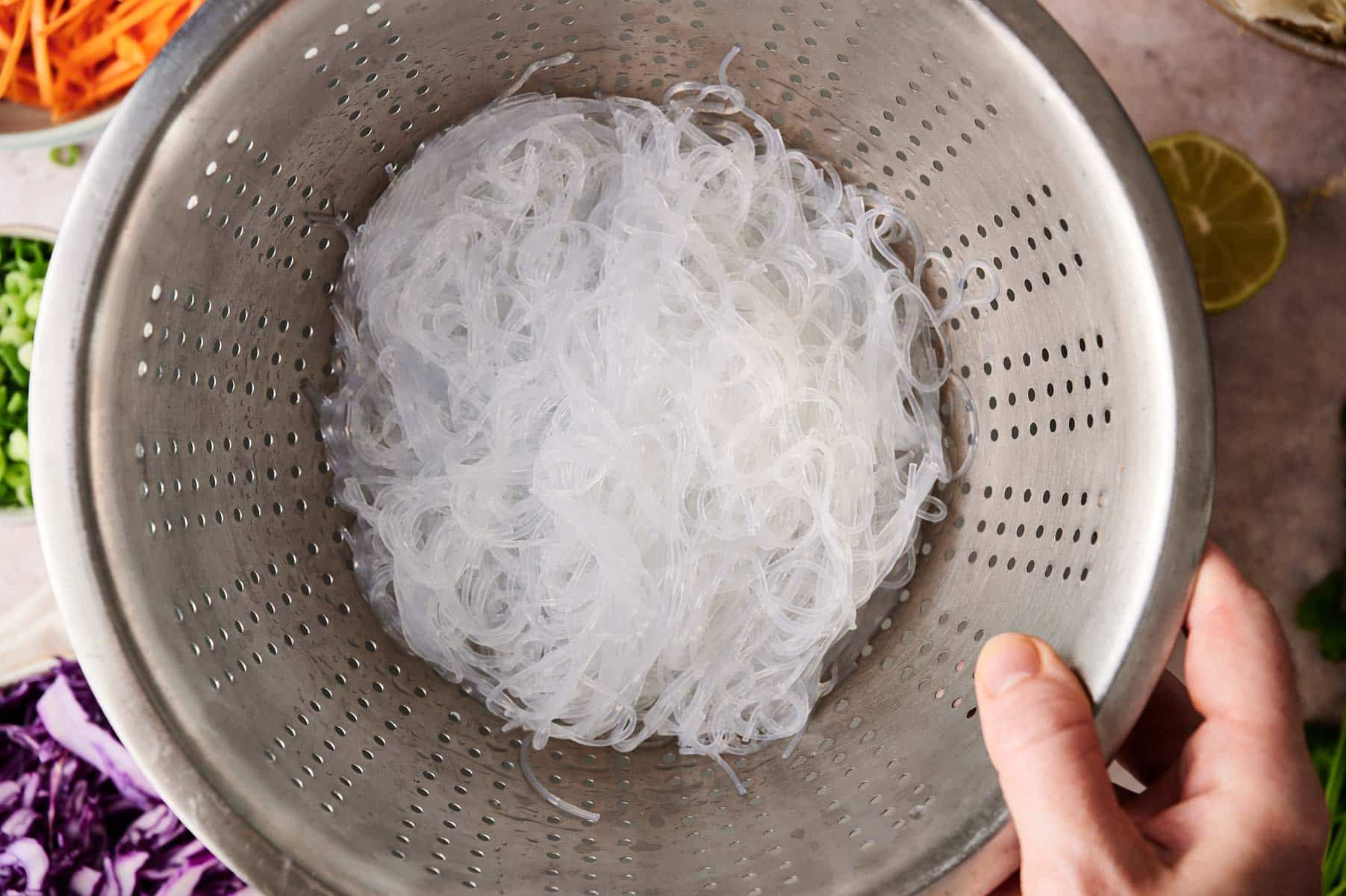 Straining the prepared rice noodles.