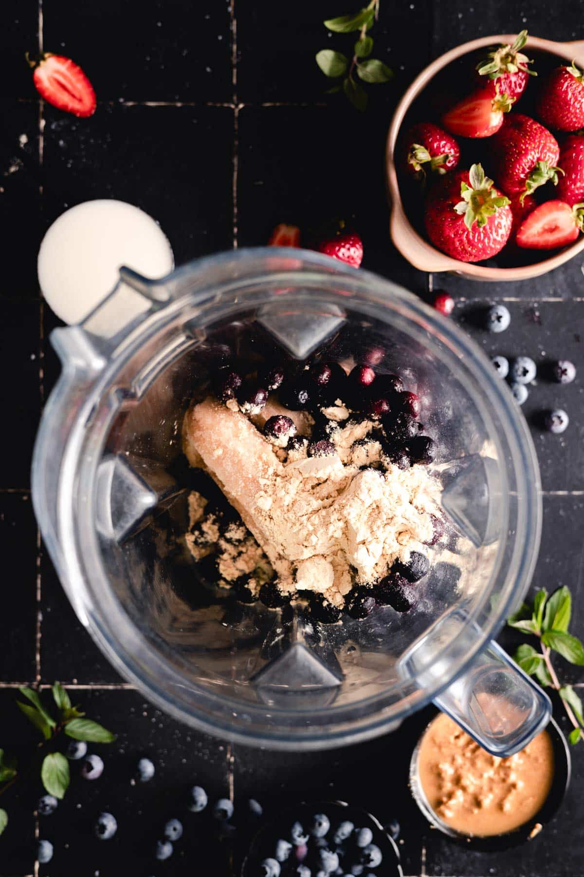 Frozen bananas, blueberries, and protein powder in a blender.