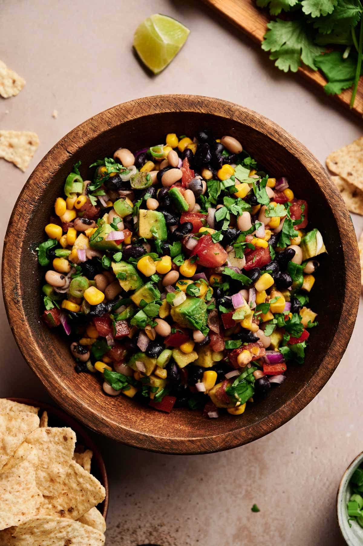 Healthy cowboy caviar on a cream counter with fresh ingredients next to it.