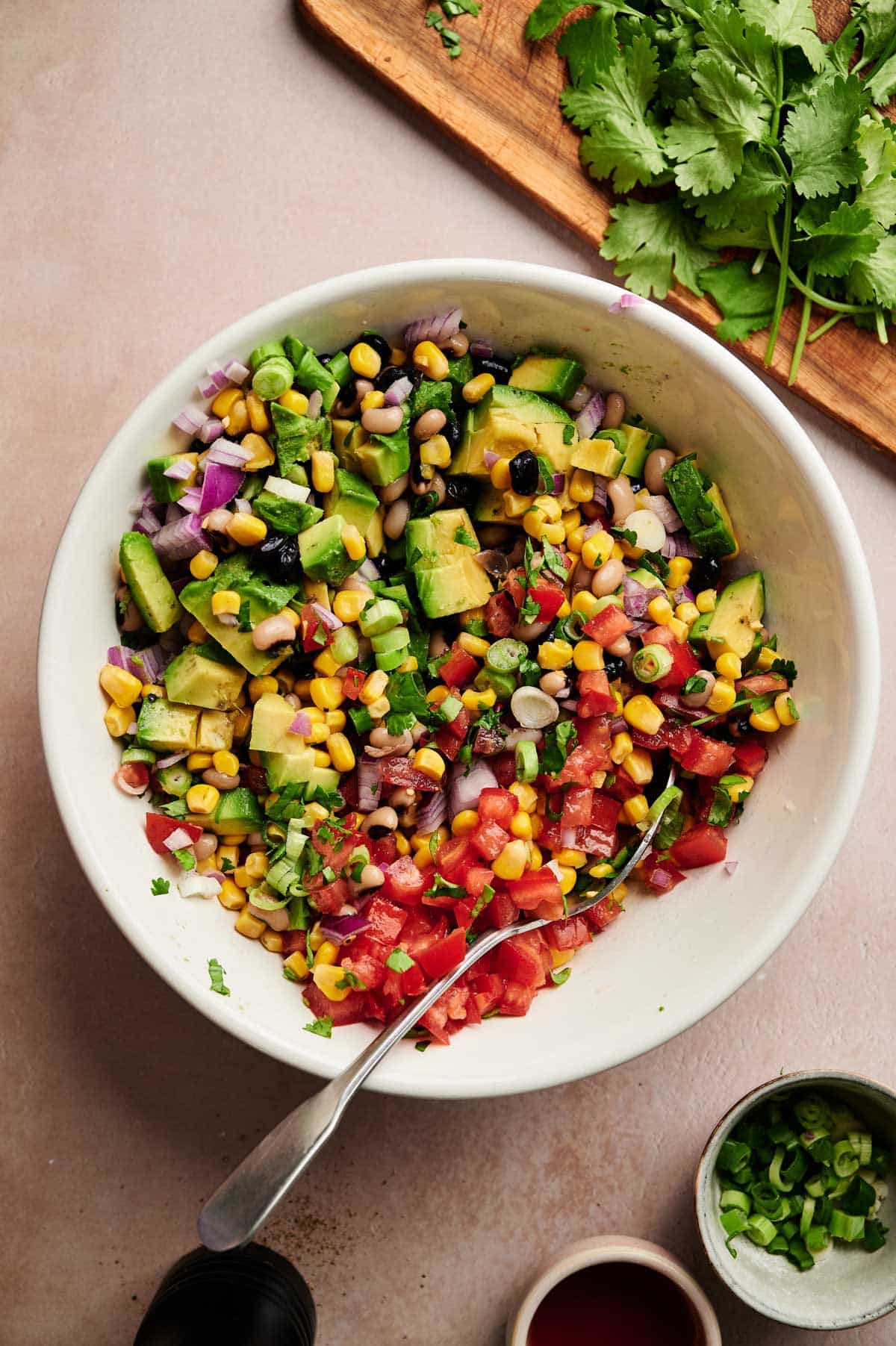 Ingredients for homemade Texas caviar in a white bowl with a spoon sticking out.